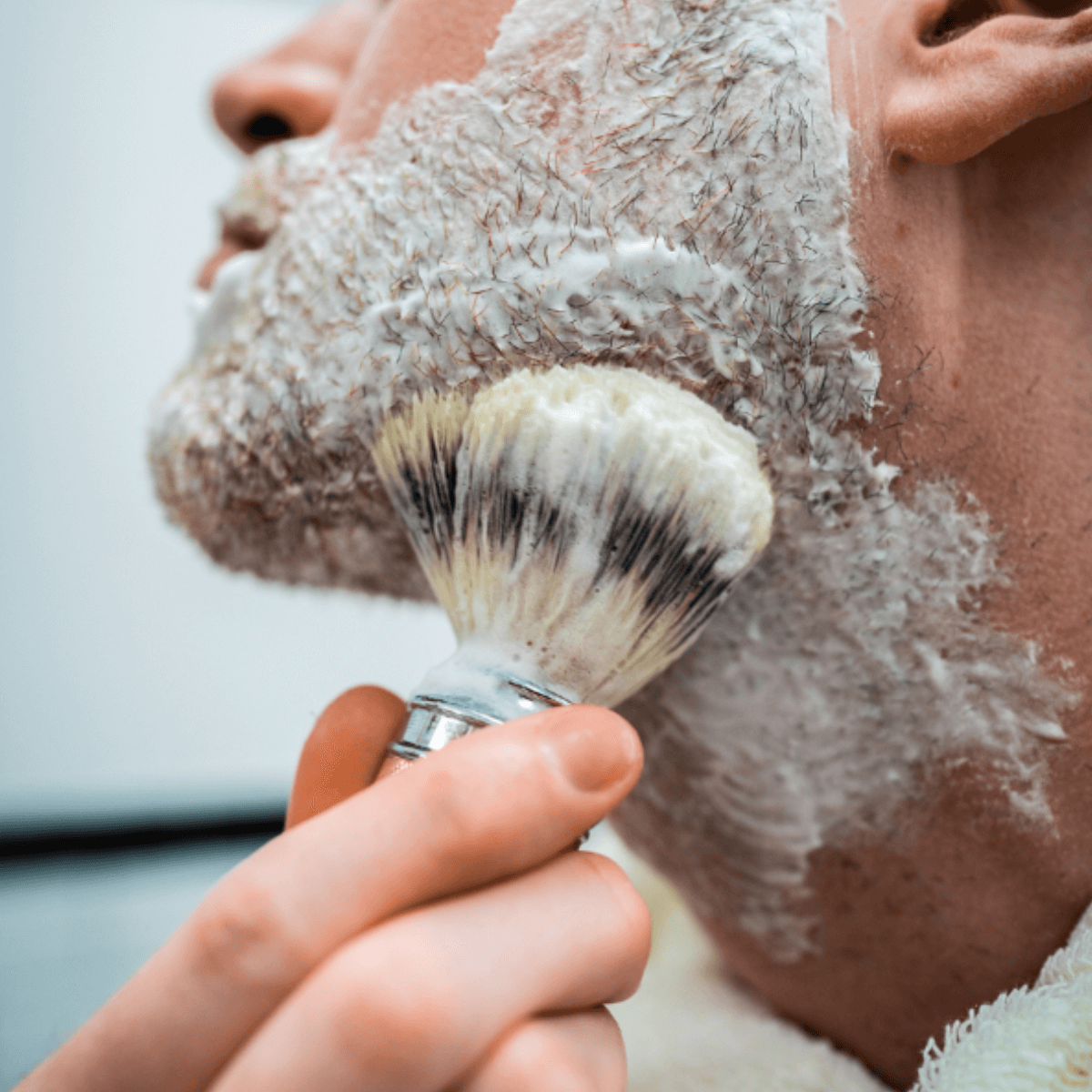 Mand påfører barberskum med klassisk barberkost – traditionel vådbarbering med tæt skum for en glat og komfortabel barbering